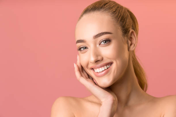 istock Attractive Woman Touching Face Smiling To Camera Over Pink Background 1208522958