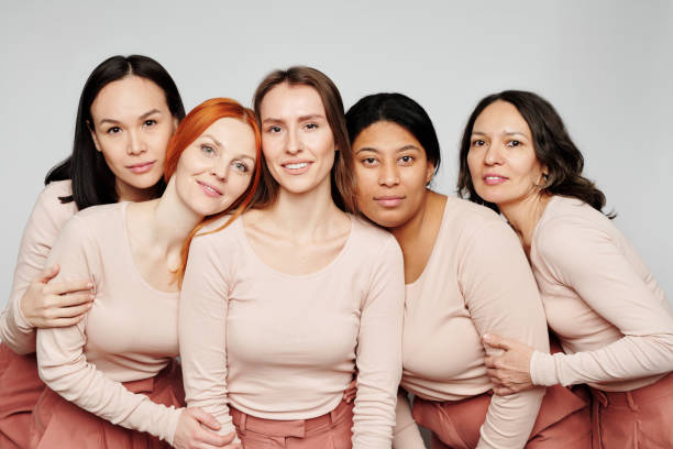 istock Portrait of content pretty multi-ethnic women hugging together while posing against white background, international womens friendship concept 1208523456