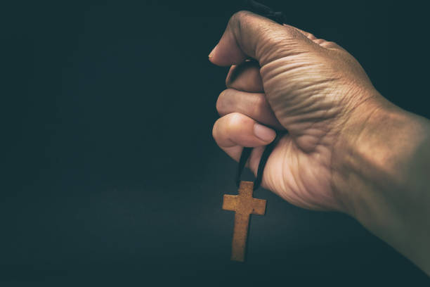 el crucifijo está en manos de un hombre que está orando por la bendición de su dios con fe. - praying human hand worshipper wood fotografías e imágenes de stock