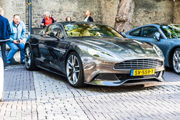 Aston Martin Vanquish sports car parked in a square in the city of Zwolle during a sunny summer morning. People in the background are looking at the cars.
