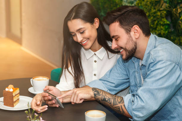 istock Boyfriend And Girlfriend Using Phone During Date In Cafe 1208525481