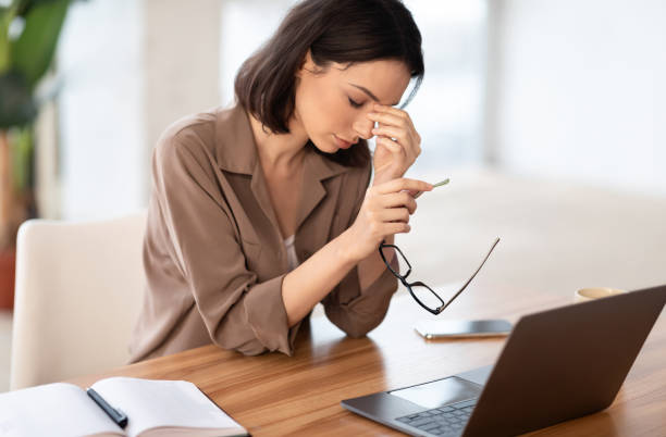 istock Exhausted manager girl massaging nose and using laptop 1208526236
