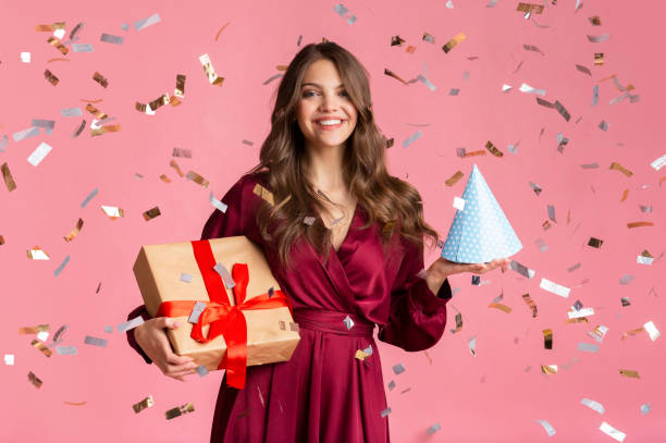 istock Happy girl with gift box and birthday hat under confetti rain 1208526264