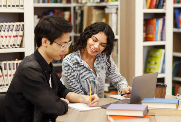 łaciński doradca siedzący i patrzący na pracę ucznia - college student student asian ethnicity high school student zdjęcia i obrazy z banku zdjęć