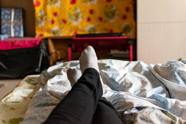 тонкие женские ноги и ноги в черных штанах и серых носках лежат на кровати среди цветных тканей текстиля - 5084 стоковые фото и изображения