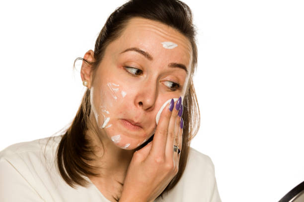 istock A woman cleaning her face with cotton pad on white background 1208532072