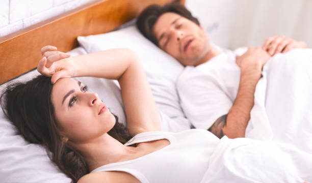 młoda kobieta cierpiąca na bezsenność, mąż śpi na bok - men women contemplation sleeping zdjęcia i obrazy z banku zdjęć