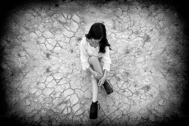 adolescente triste seduto sul terreno incrinato. donna infelice per vari concept violenza,prostituzione,tratta,bullismo - teenage sex foto e immagini stock