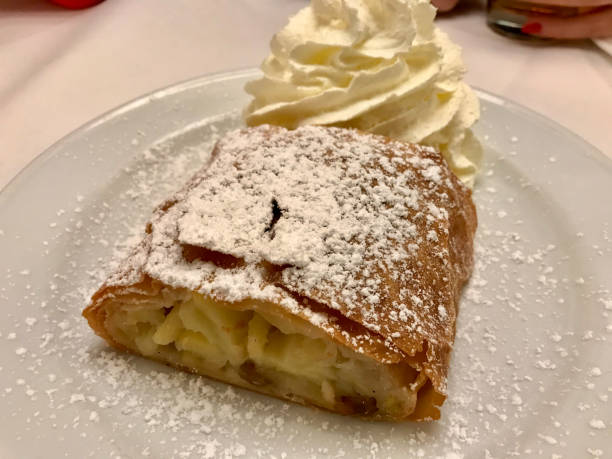 istock Authentic Traditional Apple Strudel, Apfelstrudel in Vienna, Austria. Served on a white plate, in restaurant setting. Vanilla ice cream, powdered sugar and mint leaves on top 1208536326