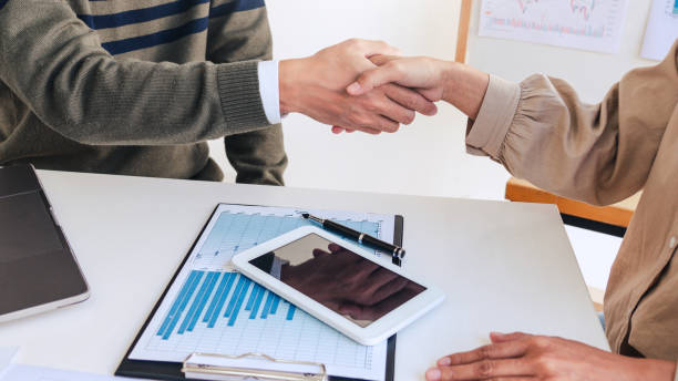 istock Midsection Of Business People Shaking Hand While Sitting In Office 1208536354