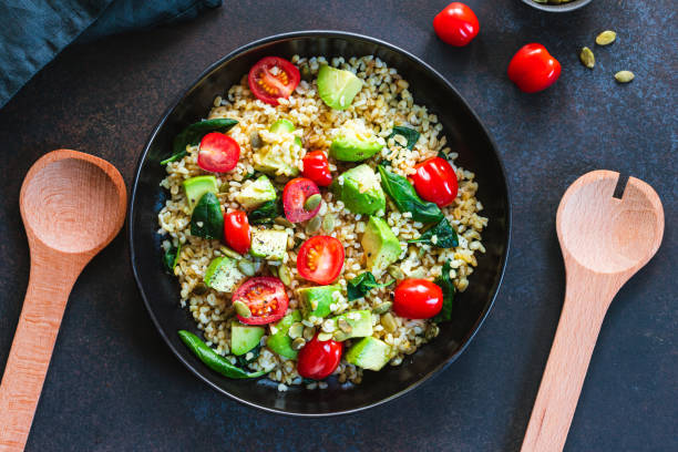 istock Healthy salad with bulgur, avocado, spinach and cherry tomatoes. Top view. 1208536385