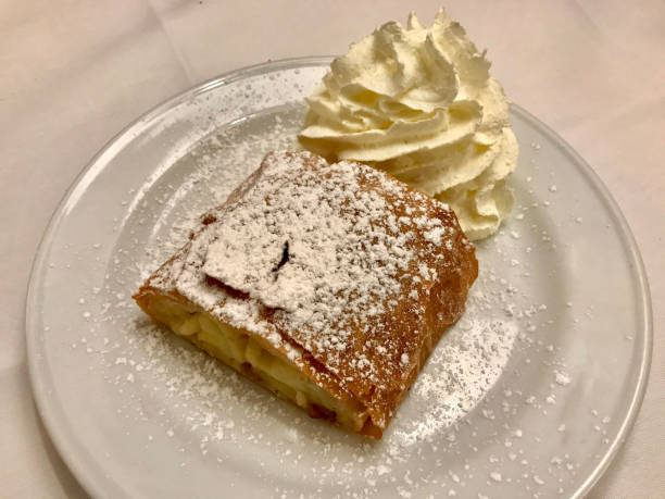 istock Authentic Traditional Apple Strudel, Apfelstrudel in Vienna, Austria. Served on a white plate, in restaurant setting. Vanilla ice cream, powdered sugar and mint leaves on top 1208536408