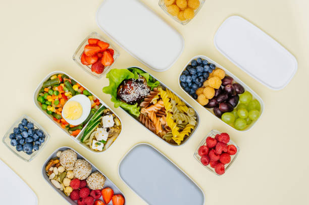 istock Pattern of plastic lunch boxes with healthy food on light yellow background 1208539293