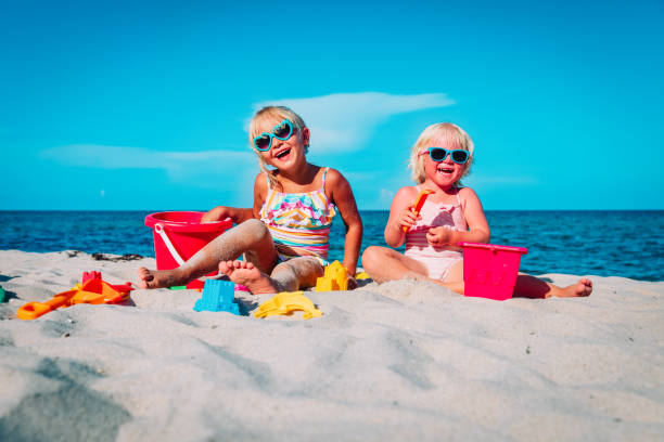 istock cute little girls play with sand on beach 1208539770