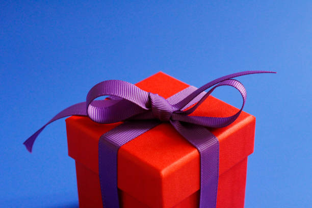istock Beautiful red gift box with a purple bow on a blue background. 1208541450
