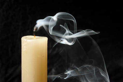 Extinct candle with smoke close-up on a dark background