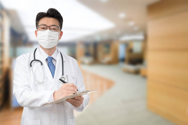 ein asiatischer männlicher arzt hält eine medizinische karte im krankenhaus, während er eine maske trägt - südkorea fotos stock-fotos und bilder