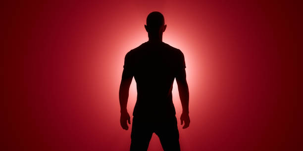 istock Silhouette of a man. Red spotlight behind him 1208545379