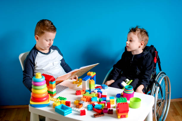 istock Boy is reading a book to a boy in a wheelchair 1208548091