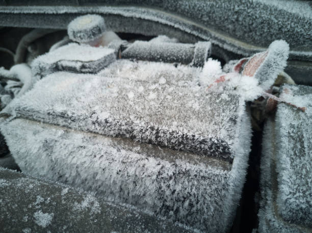 istock Car battery close-up. The engine compartment is covered with snow and ice after a long parking. 1208549376