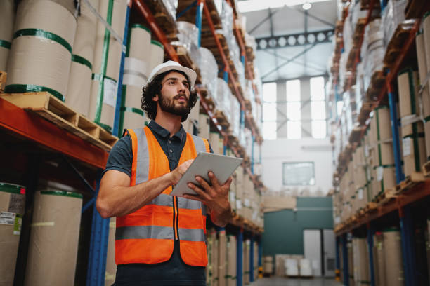 istock Concentrated successful warehouse manager inspecting inventory check from digital tablet while standing between shelf working 1208552021