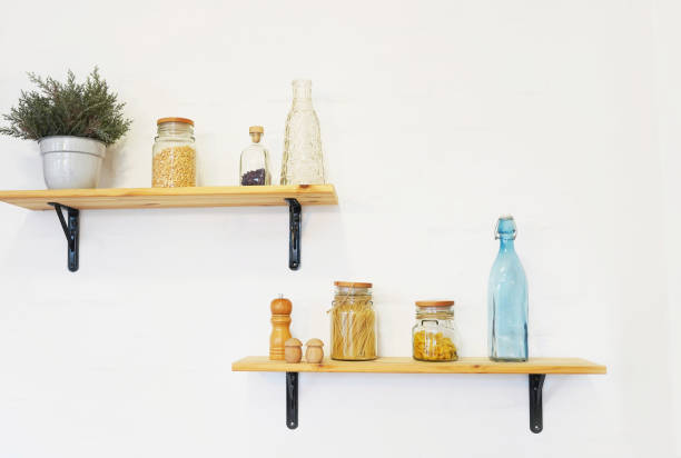 istock Decorative shelves on white brick wall with vintage bottles and wicker jars on it 1208553867