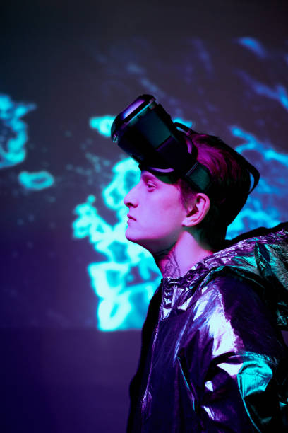 istock Side view of thoughtful young man in reflective jacket believing in new reality standing against neon background 1208554001