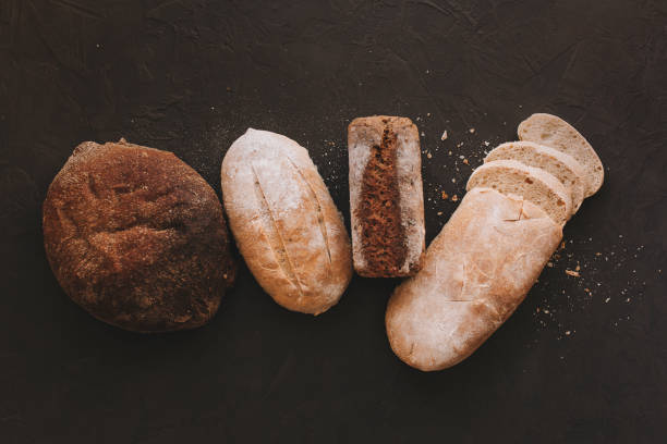 istock Various crispy bread and buns on the stone table, Loaf of fresh baked artisan sliced rye bread over dark texture background. Top view, copy space 1208554773