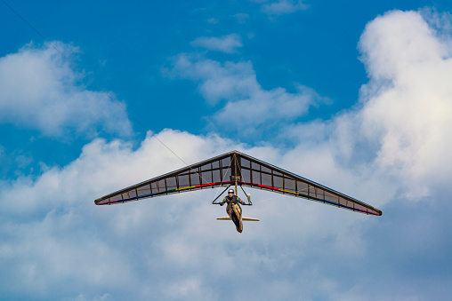 Dream of flying come true. Hang glider pilot and his rainbow colored wing.