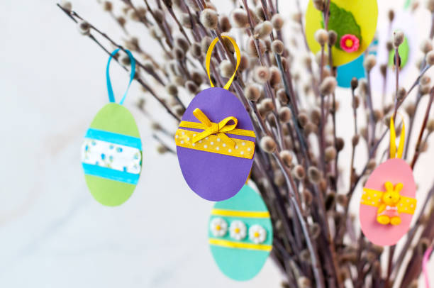 istock Easter eggs cutted from color paper decorated with ribbon and buttons on willow branches 1208557948