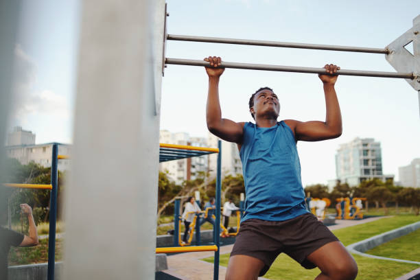 istock Front view of a strong african american male athlete doing pull-up on horizontal bar in the public gym park 1208558499