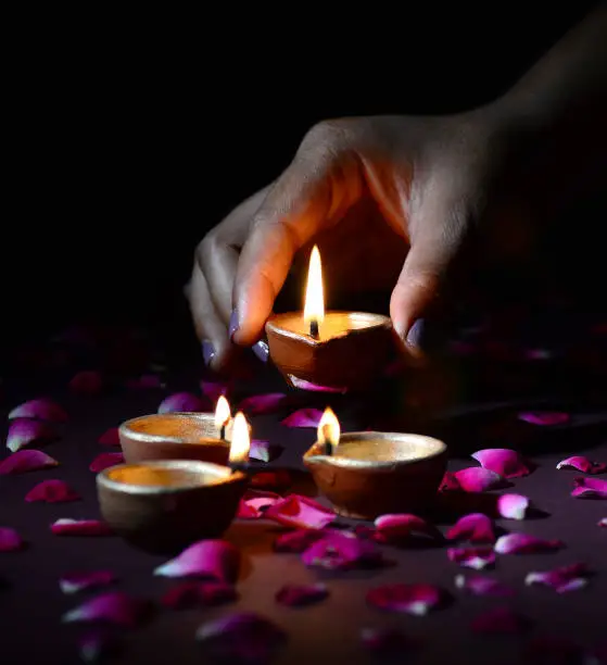 Hand holding and arranging lantern (Diya) during Diwali Festival of Lights