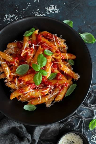 istock Penne pasta with tomato sauce, parmesan cheese and basil on dark backgound. 1208559314