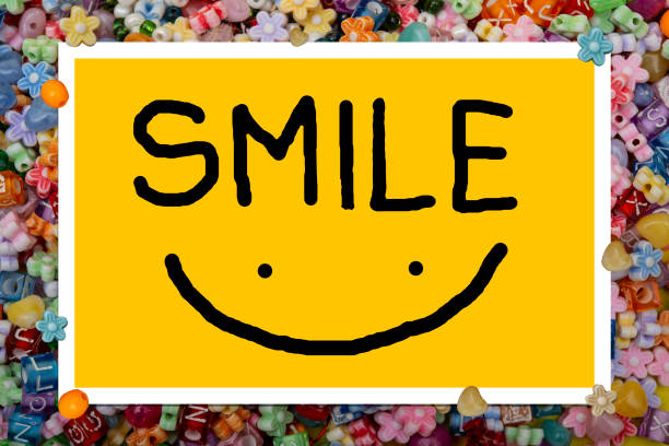 Happiness and approval concept - one young woman holding an anthropomorphic smiley face. She is looking at the camera and smiling.