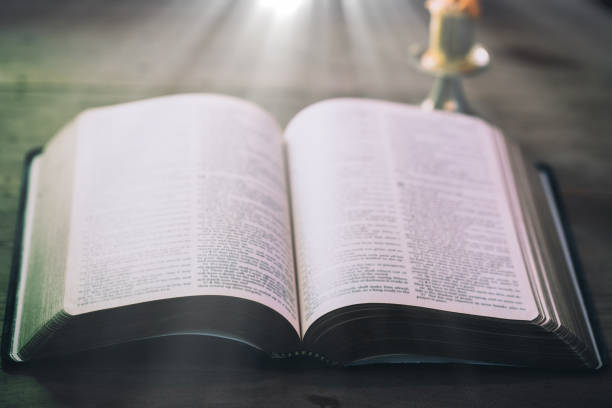 istock Opened Holy Bible book on wooden table against window light 1208562155