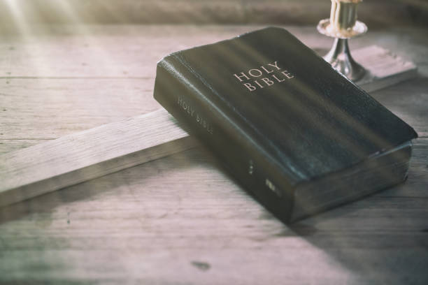 istock Bible on old oak wooden table with window light 1208562181