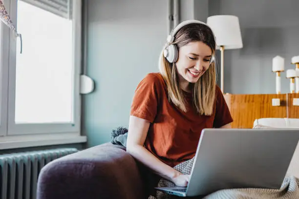 Young woman is using laptop and working in the living room