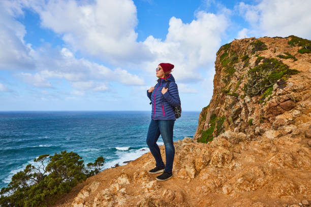 jovem turista no cabo cabo da roca parado na borda rochosa do penhasco. as ondas do oceano quebram nas rochas no fundo do penhasco - hiking coastline waters edge sunny - fotografias e filmes do acervo