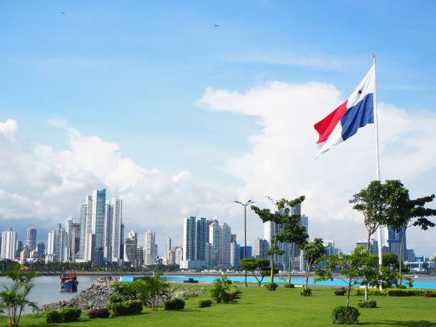 ciudad de panamá / panamá - 1 de septiembre de 2019: horizonte urbano con hierba verde y bandera enarbolando. cielo azul y nubes blancas. - panamá fotografías e imágenes de stock