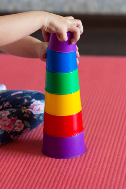 les mains d’enfants font pyramide utilisant des tasses colorées d’empilage - cup child geometric shape stacking photos et images de collection