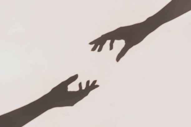 istock Grey shadows of hands reaching each other on the wall. Abstract blurred effect. 1208570494
