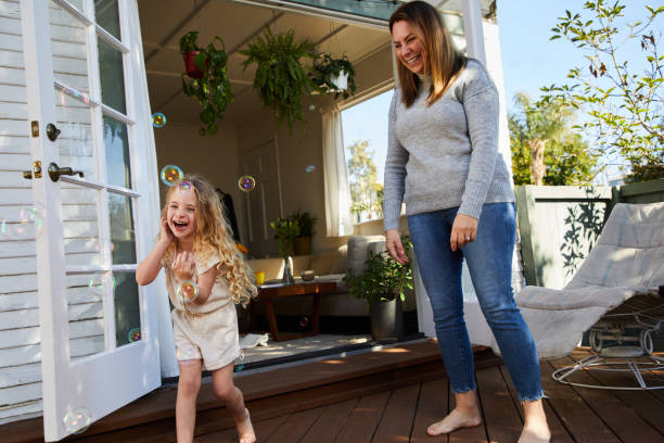 istock Laughing little catching bubbles with her mom on their patio 1208572378