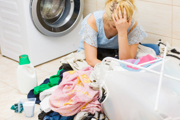istock Unhappy girl sorting dirty clothes laundry. 1208574107