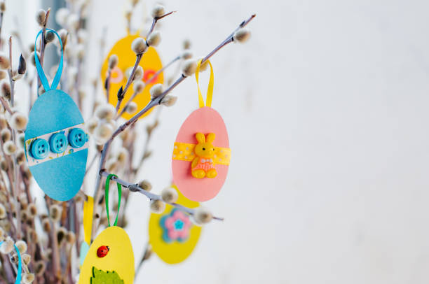 istock Easter eggs cutted from color paper decorated with ribbon and buttons on willow branches 1208576765