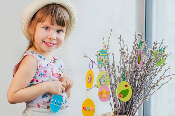 istock Beautiful little girl hanging Easter eggs cutted from color paper 1208576796
