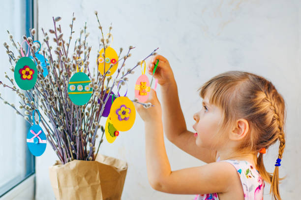 istock Beautiful little girl hanging Easter eggs cutted from color paper 1208576802