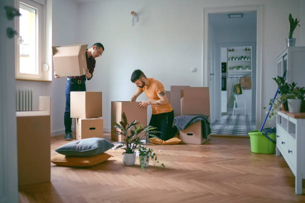 homosexual couple unpacking boxes in a new home - moving house apartment couple box imagens e fotografias de stock
