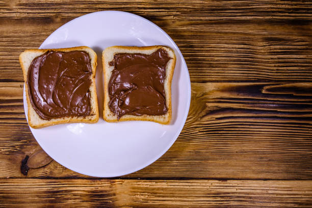 Two sandwiches with chocolate spread on a white plate. Top view
