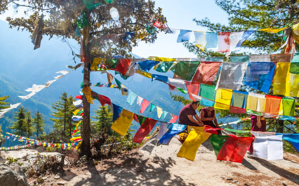 moine bouddhiste dans les vêtements rouges traditionnels et les drapeaux bouddhistes tibétains de prière multicolores de poumon ta dans l’himalaya sur le chemin au monastère de taktsang ou au nid de tigre - monastère de taktsang photos et images de collection