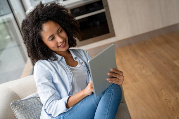 istock Woman at home reading on her tablet computer 1208580207